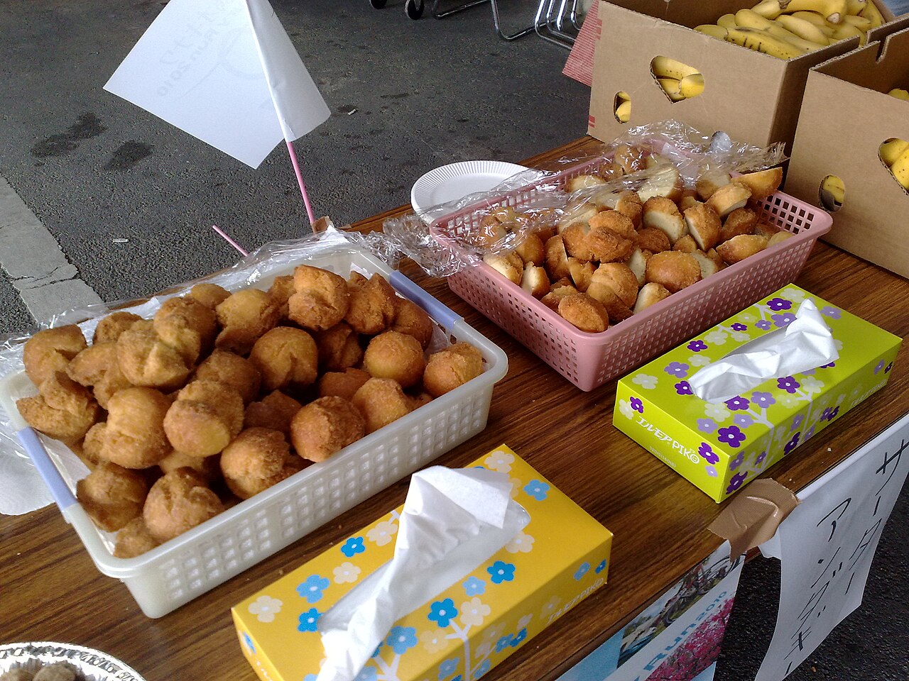 Baskets of golden andagi, Okinawan-style deep-fried doughnuts, on a vendor table.